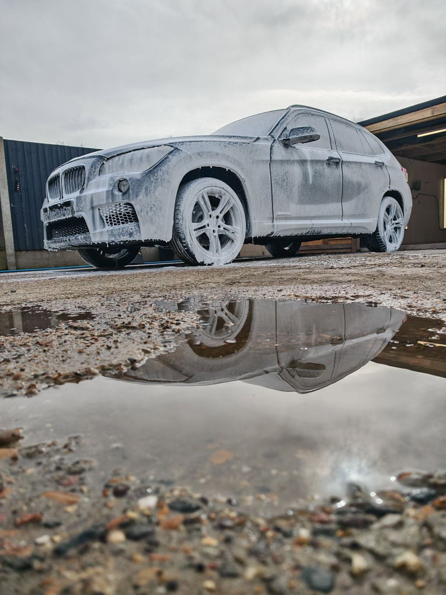 White BMW X1 covered in snow foam during exterior deep clean service