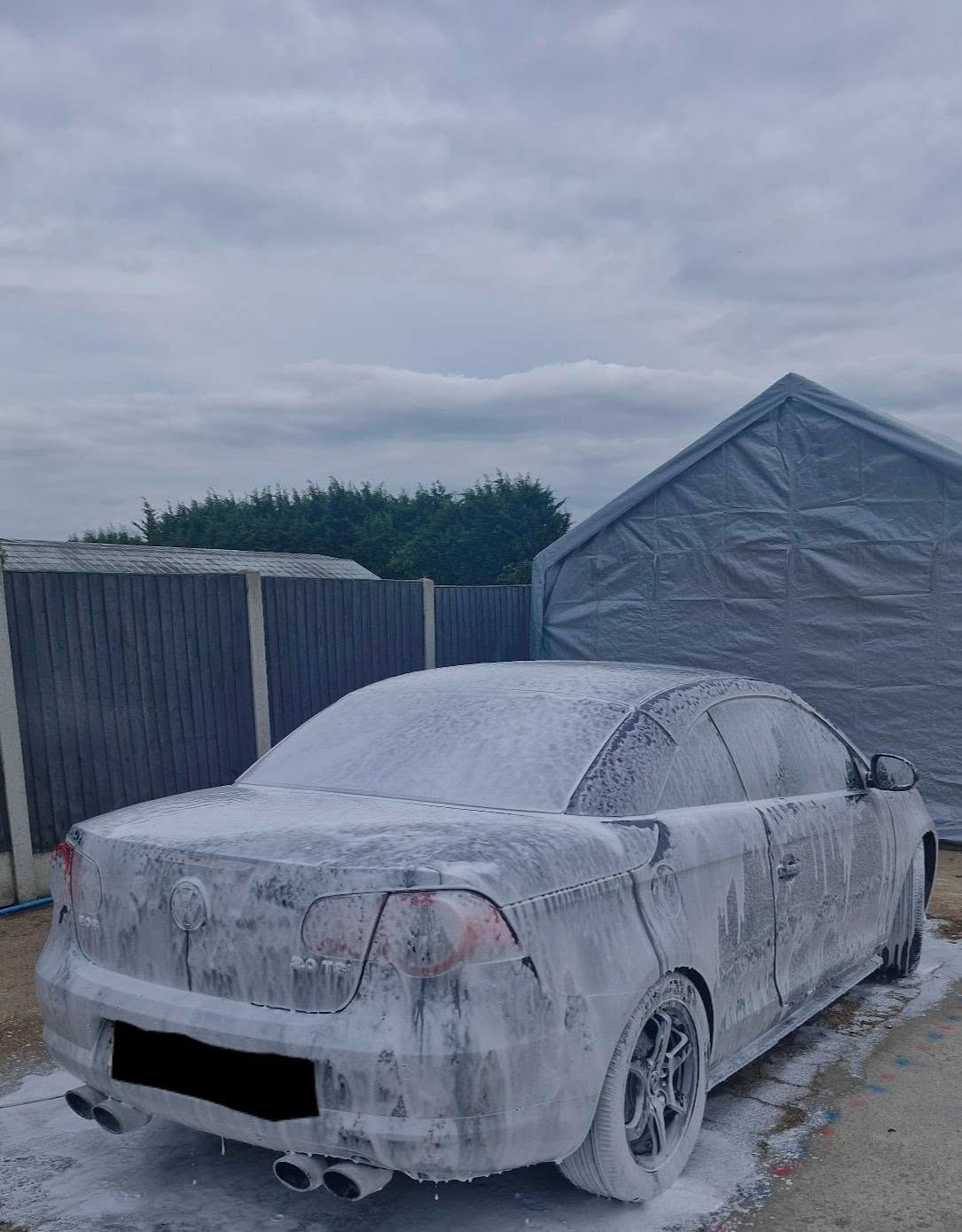 Rear view of a VW Eos covered in snow foam during exterior deep clean