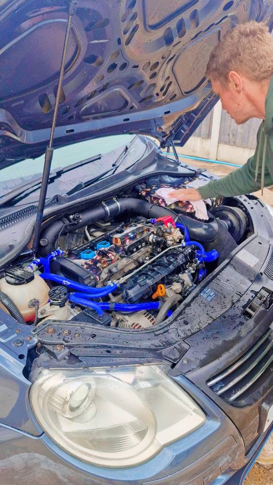 VW engine bay being hand-detailed with a microfibre cloth